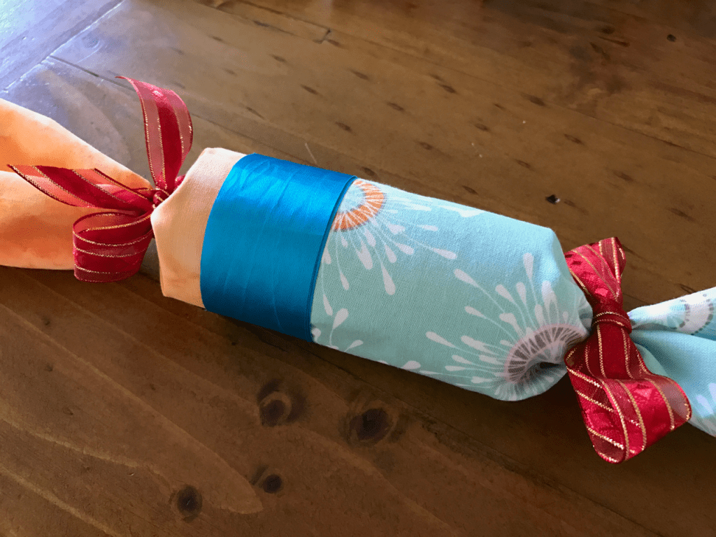 Picture of a cloth Christmas cracker with napkins and bows.