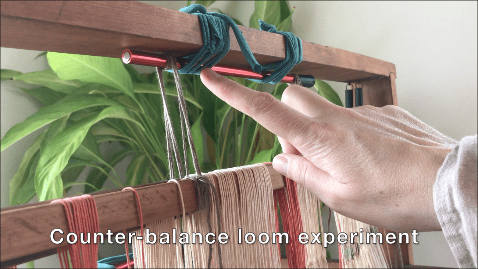 Picture showing a table loom with a hand pointing to the top beam
