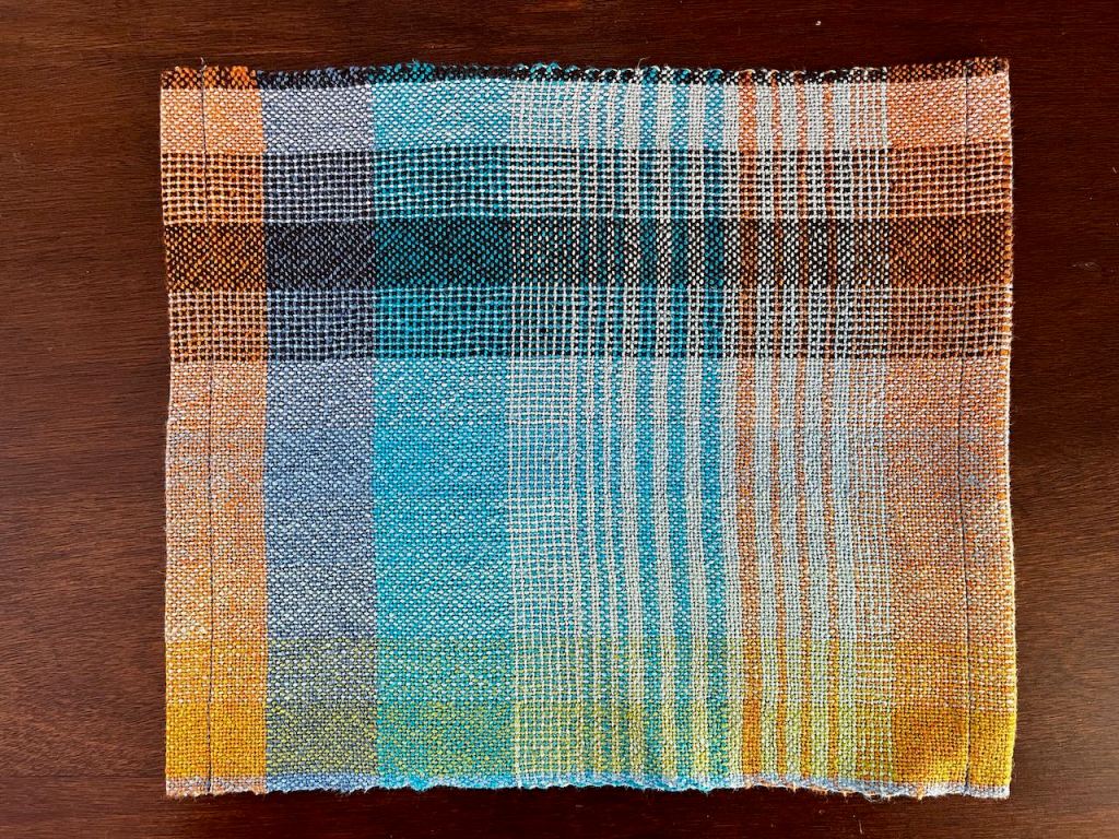 A vibrant weaving sample with orange and peacock colours
